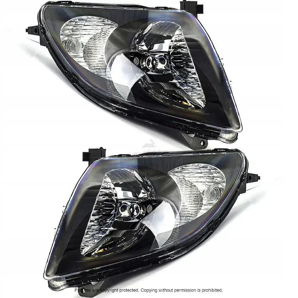 Frontlykter Suzuki Swift 05-07 med klart glass og svart innramming, sett fra skrå vinkel på hvit bakgrunn.