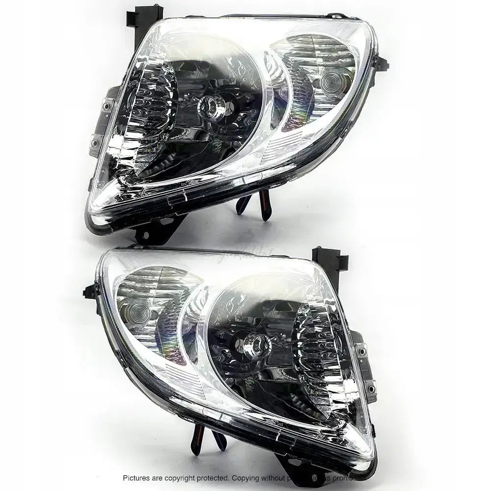 Frontlykter Suzuki Swift 05-07 H4 med kromrefleks, sett skrått mot lyst underlag med synlige fester.