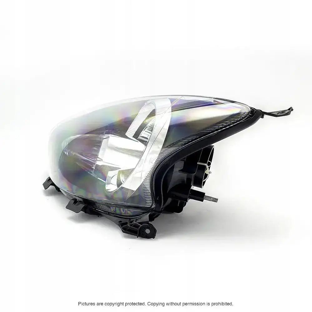 Hovedlys Toyota Aygo 08-12 H4 med klar plastfront og svarte detaljer sett fra siden og litt ovenfra.