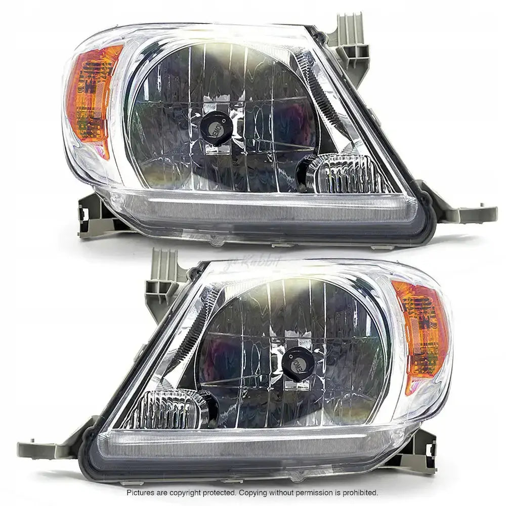 Frontlykter Toyota Hilux 04-08 H4 sett fra skrå front med oransje blinklysfelt og refleksjonsdetaljer.