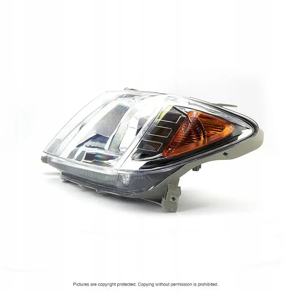 Hovedlys Toyota Hilux 04-08 H4 sett skrått forfra med klar plast, oransje reflektor og kromdetaljer.
