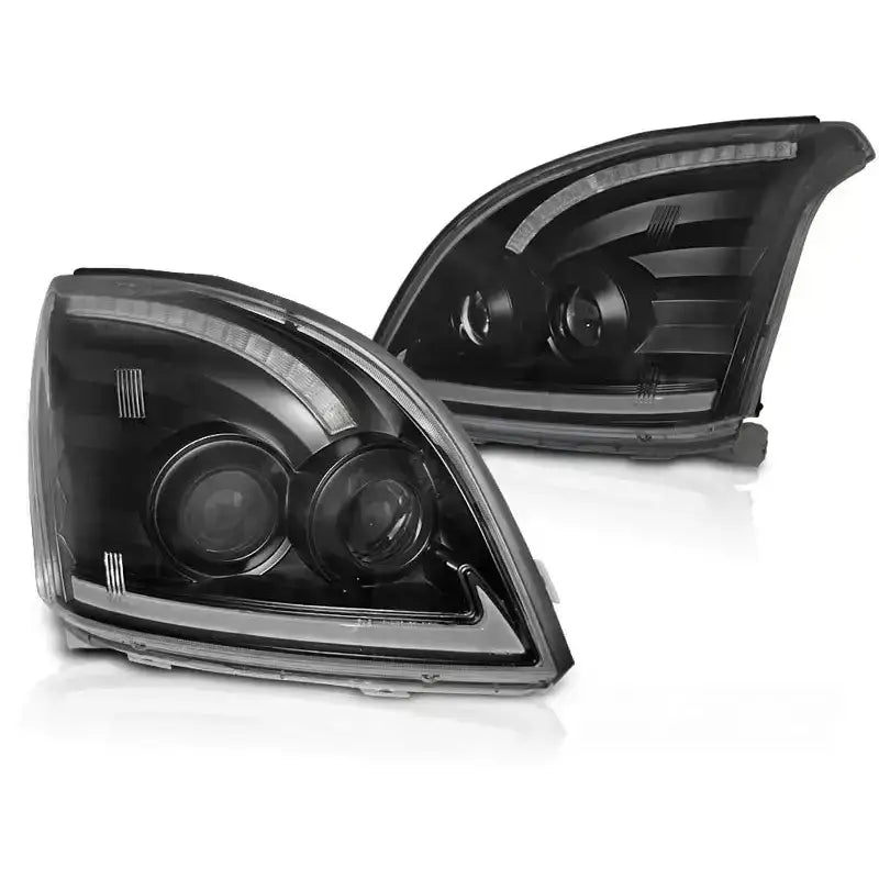 Frontlykter Toyota Land Cruiser J120 Tube Light SEQ LED Black med doble projektorlinser og LED-striper.