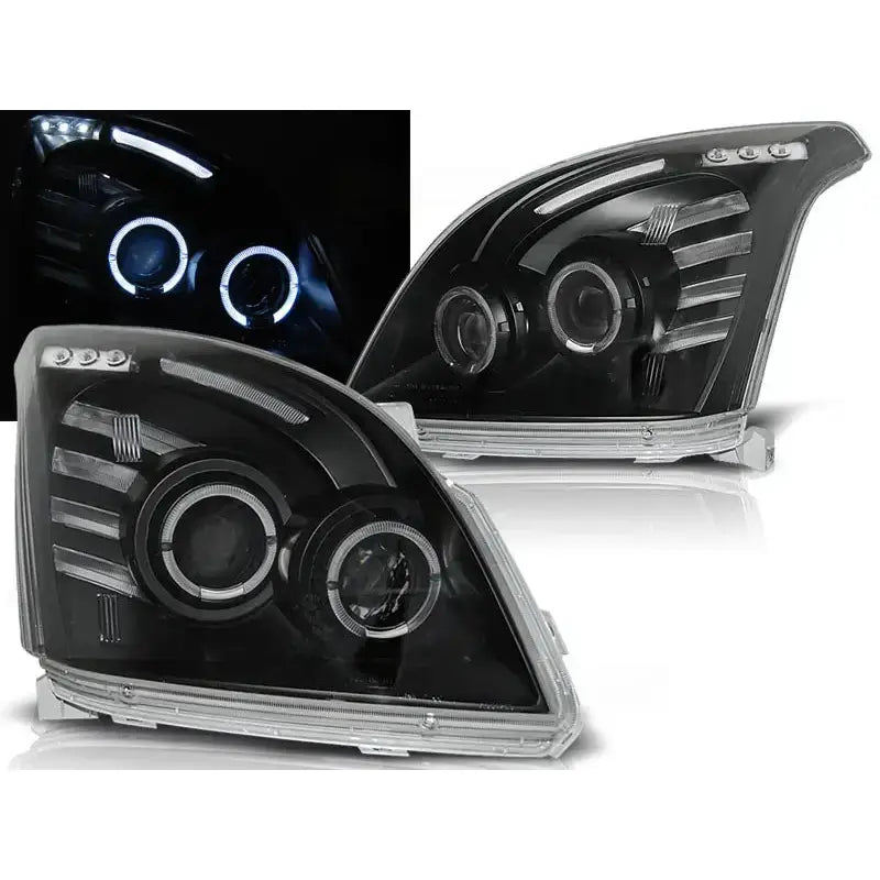 Frontlykter Toyota Land Cruiser J120 med sorte hus, klare linser og LED-ringer, sett fra skrå vinkel.