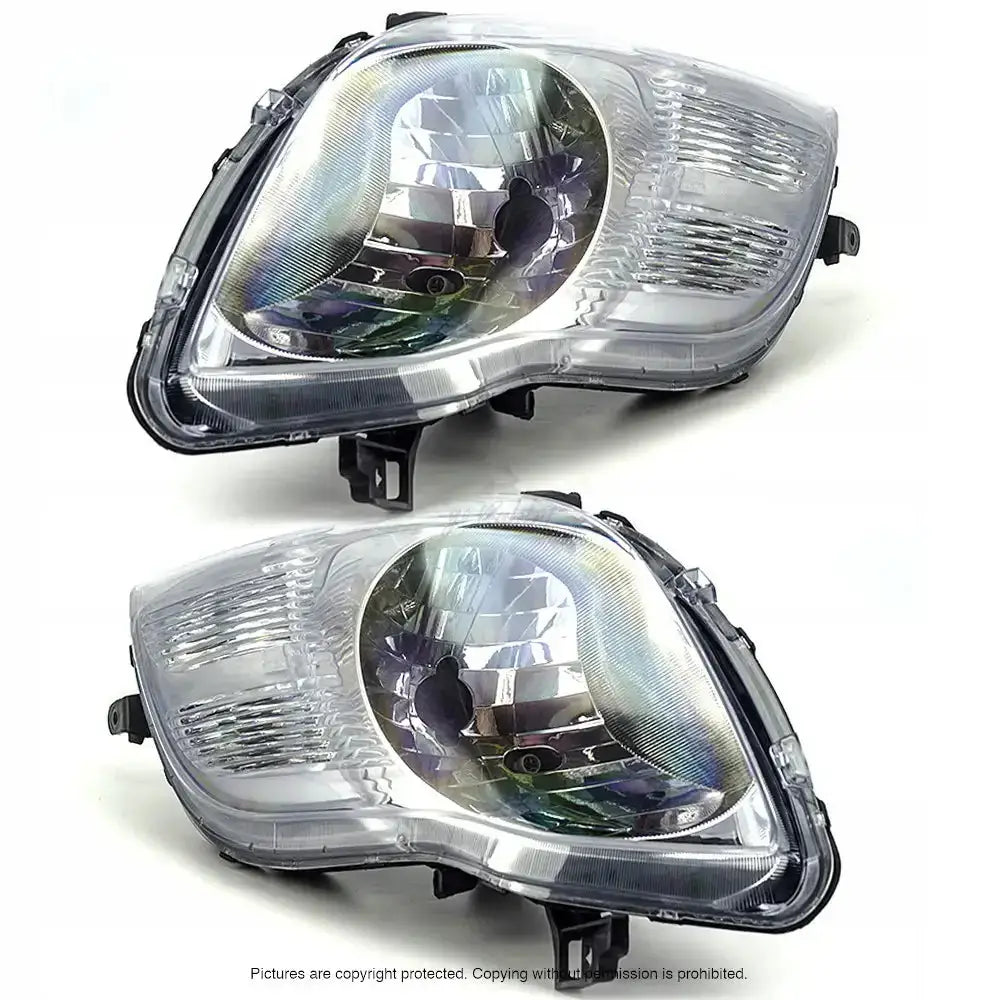 Frontlykter Toyota Yaris 05-10 H4 sett ovenfra med reflektorer og monteringsfester på hvit bakgrunn.