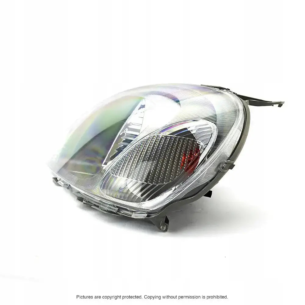 Headlights Toyota Yaris 99-03 H4 med klare reflektorer og sølvdetaljer, sett fra skrå forside.