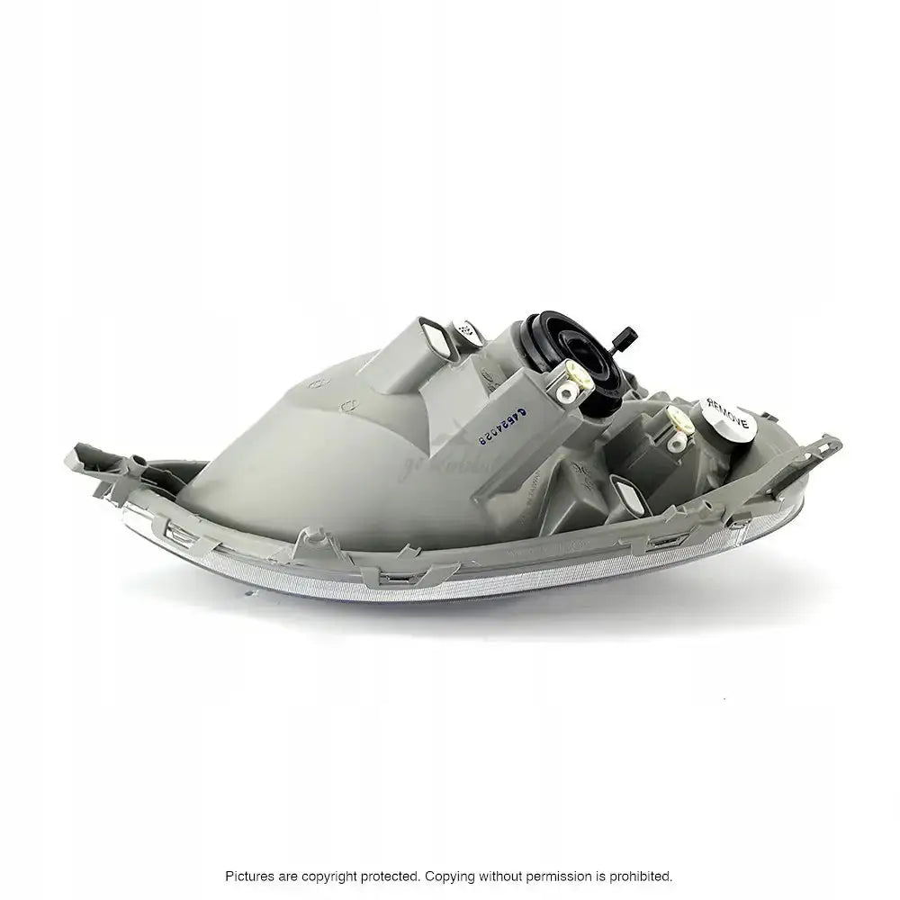 Hovedlykter Toyota Yaris 99-03 bakside med skruefester og koblingspunkter synlige, grå plast mot hvit bakgrunn.