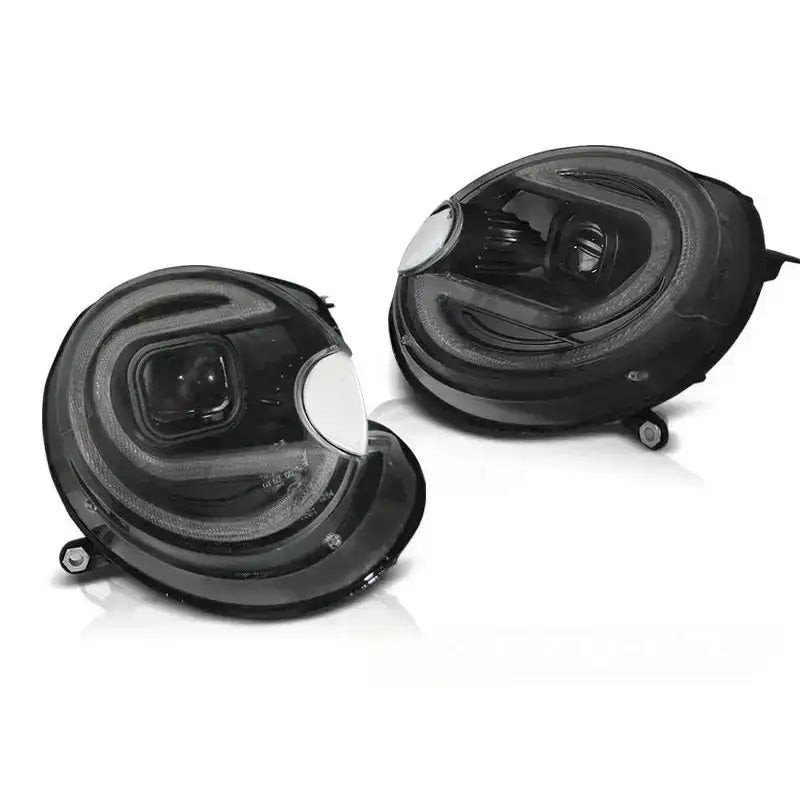 Frontlykter Tube Light Black til Mini Cooper 06-14, runde med LED-lysbaner, vist fra skrå vinkel.