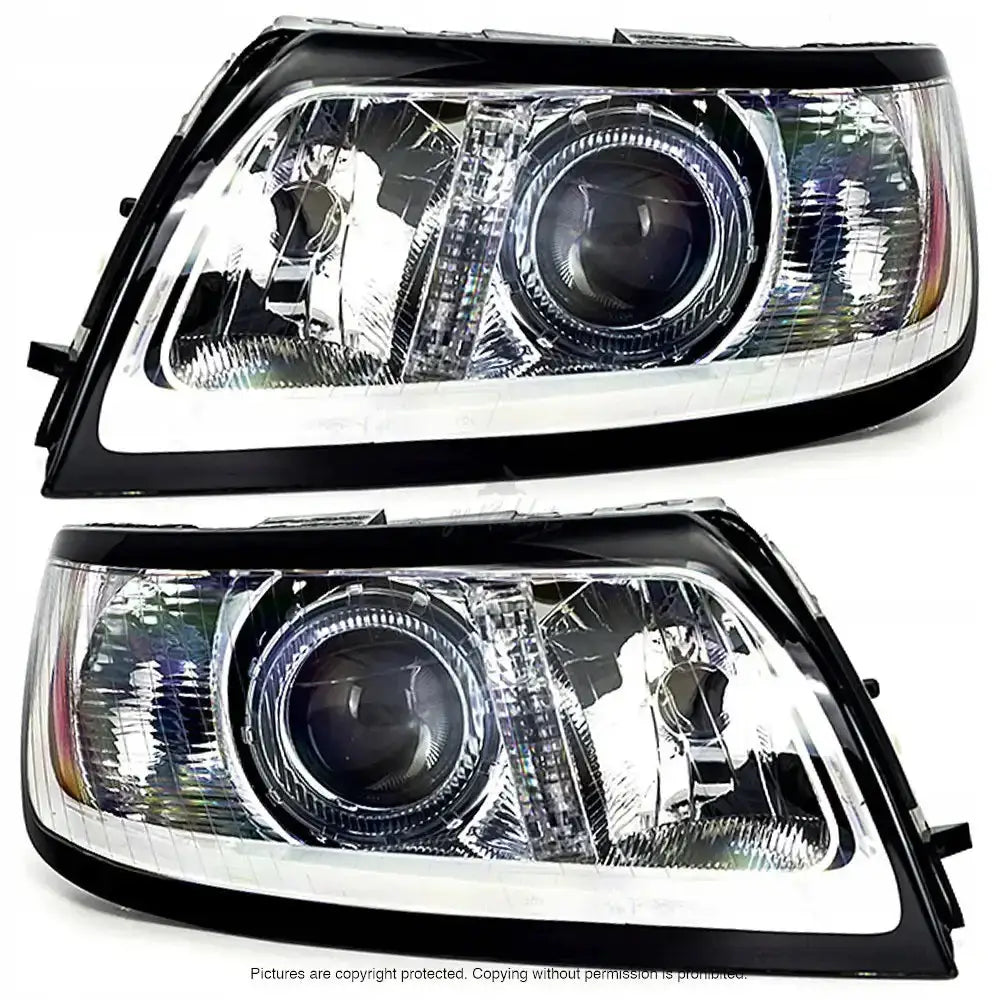 Frontlykter Volvo V50 07-12 med klar plast, sorte og kromdetaljer, sett forfra mot hvit bakgrunn.