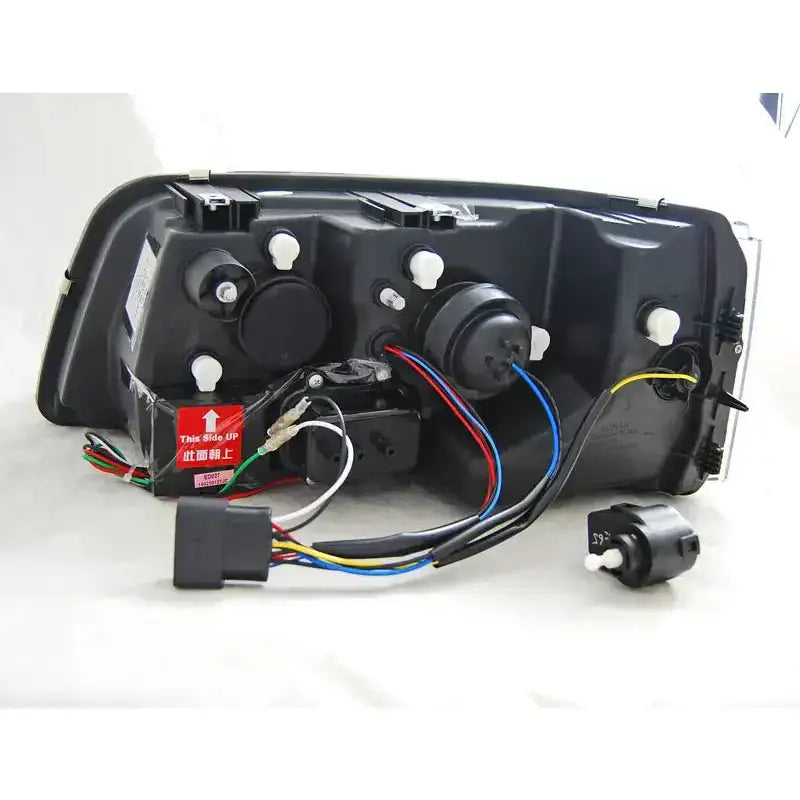 Hovedlykter Vw T5 Tru DRL Black sett bakfra med ledninger, plugger og rød etikett synlig.