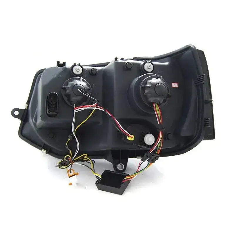 Frontlykter Vw T5 bakside med svart deksel, ledninger, to runde lokker og synlige festepunkter.