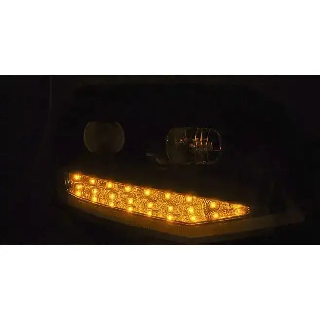 Frontlykter Vw T6 15- Black Tube Light med gule LED-lys og reflekterende bakplate, sett forfra i mørket.