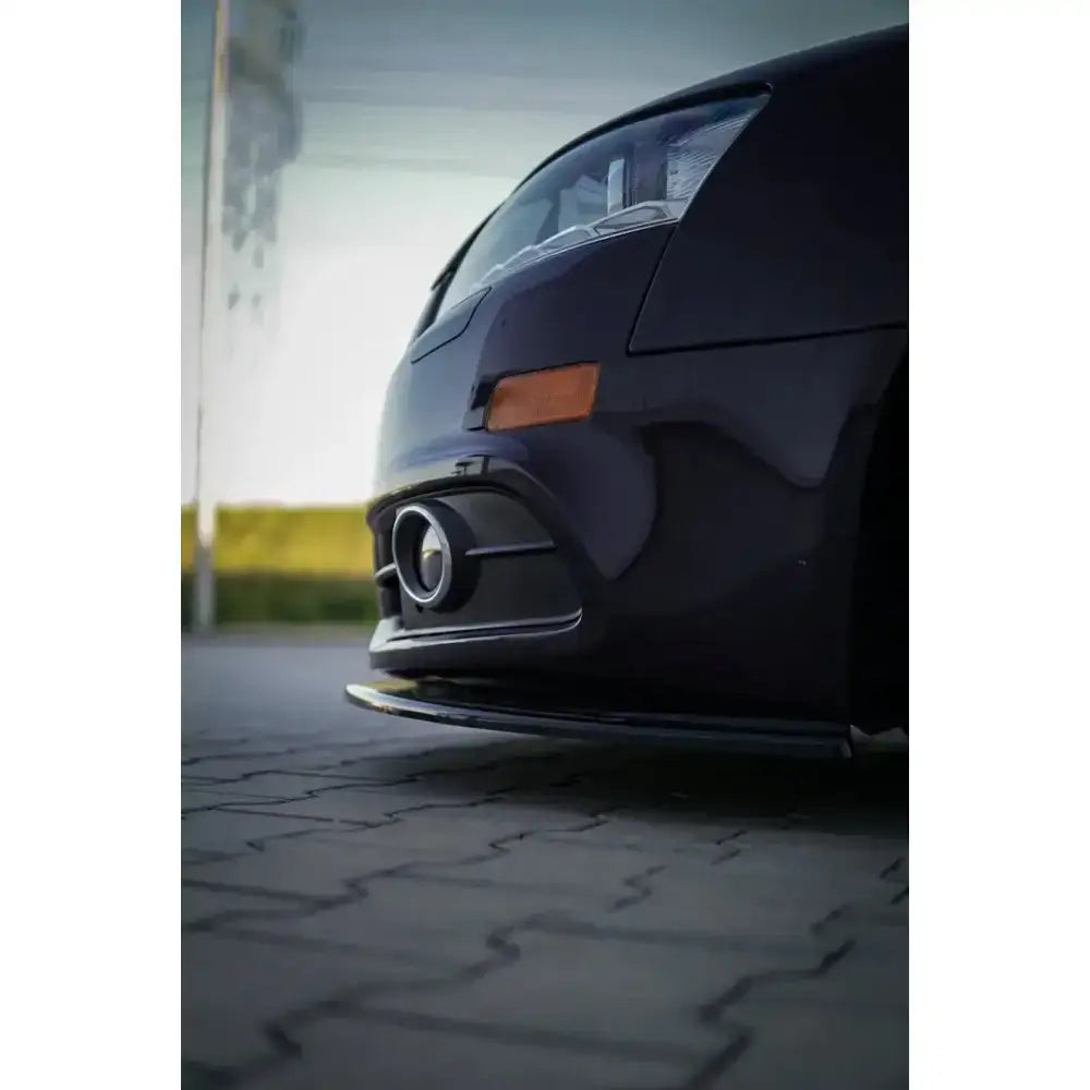 Spoiler til Audi A6 C6 S-Line Fl Sedan i sort, lav vinkel med grill og rund innsats, asfalt i bakgrunnen.
