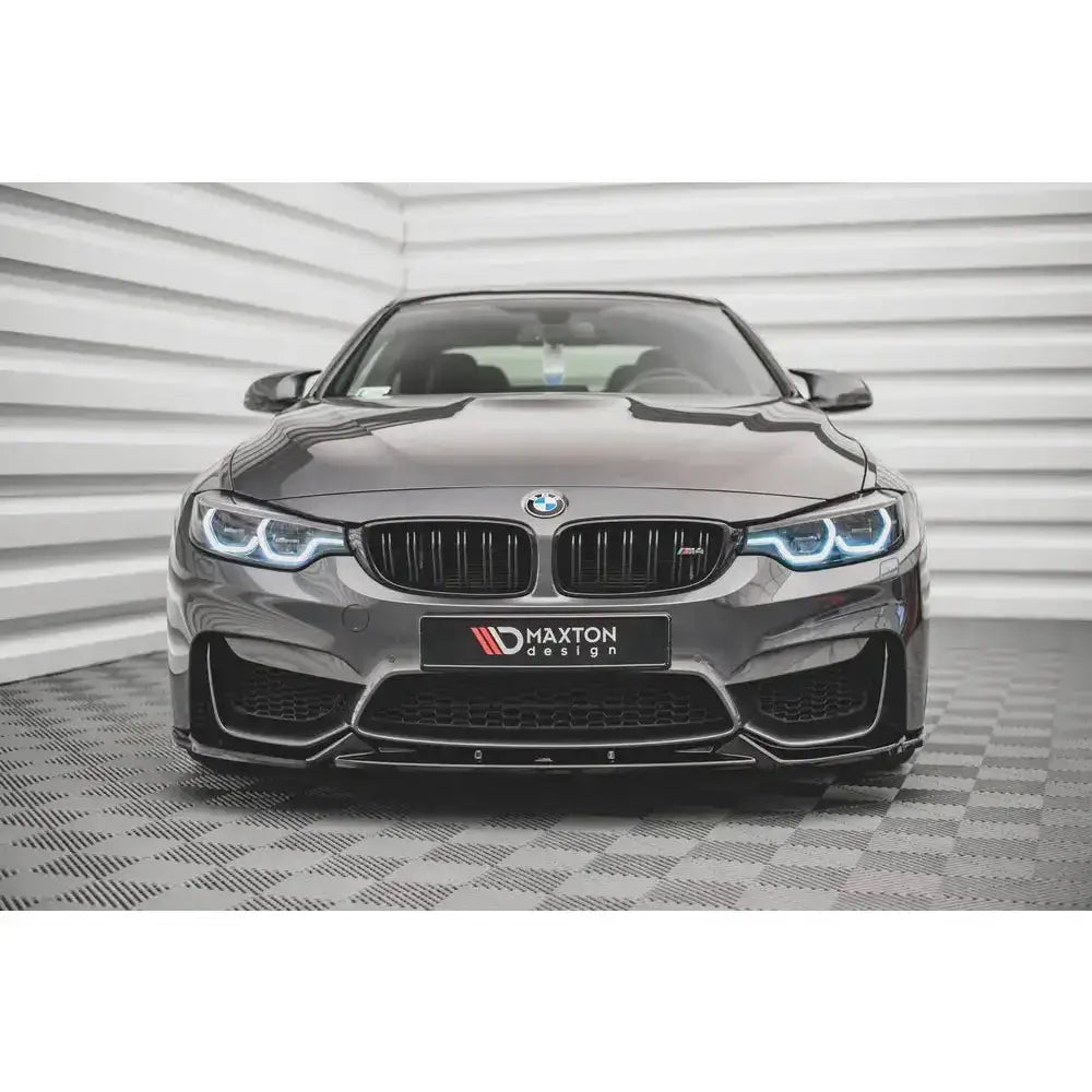 Spoiler på BMW M4 F82 14- med blå frontlykter, sportslig grill og markerte luftinntak sett forfra.