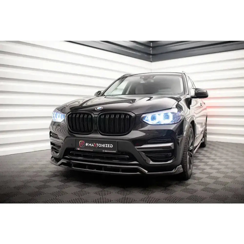 Spoiler på BMW X3 G01 med sorte felger, LED-frontlykter og markant grill, sett forfra innendørs.