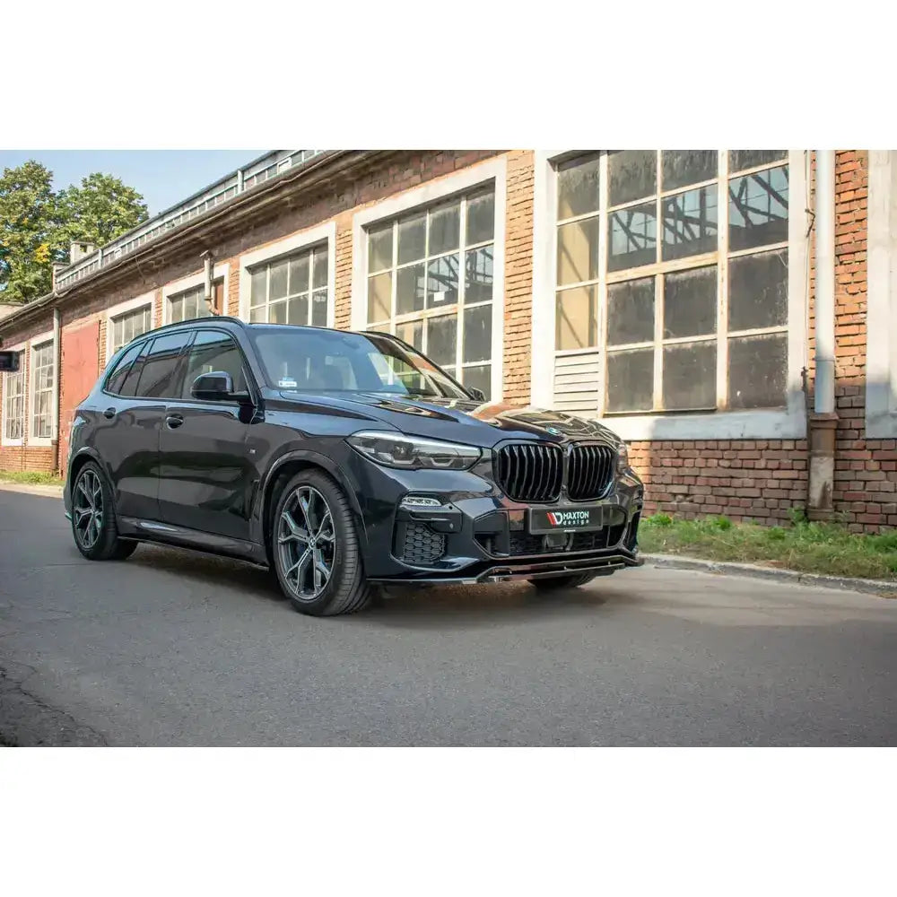 Frontspoiler på Bmw X5 G05 M-Pack, sort SUV sett skrått forfra med store felger.