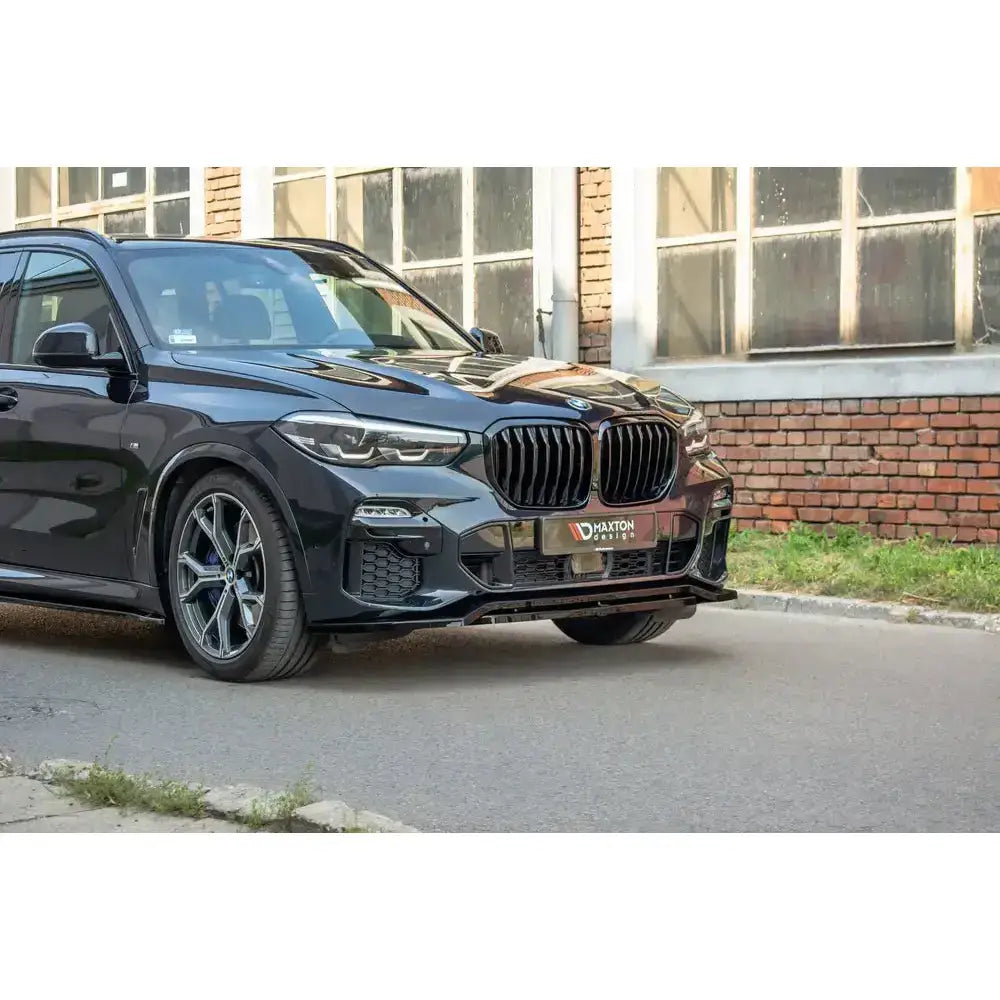 Front splitter på BMW X5 G05 M-Pack, sort SUV med sportslige detaljer og sorte felger, sett skrått forfra.