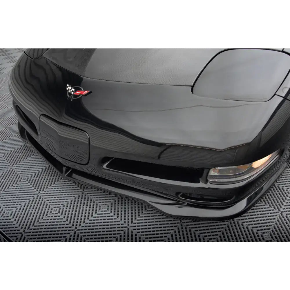 Frontspoiler Chevrolet Corvette C5 i blank sort sett skrått ovenfra med synlig logo og del av lykt.