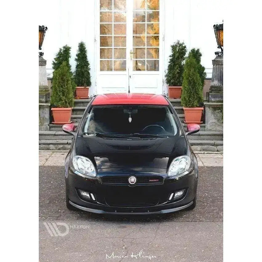 Frontleppe på Fiat Bravo II, svart bil med rødt tak, sett forfra foran bygning med trapper og grønne planter.