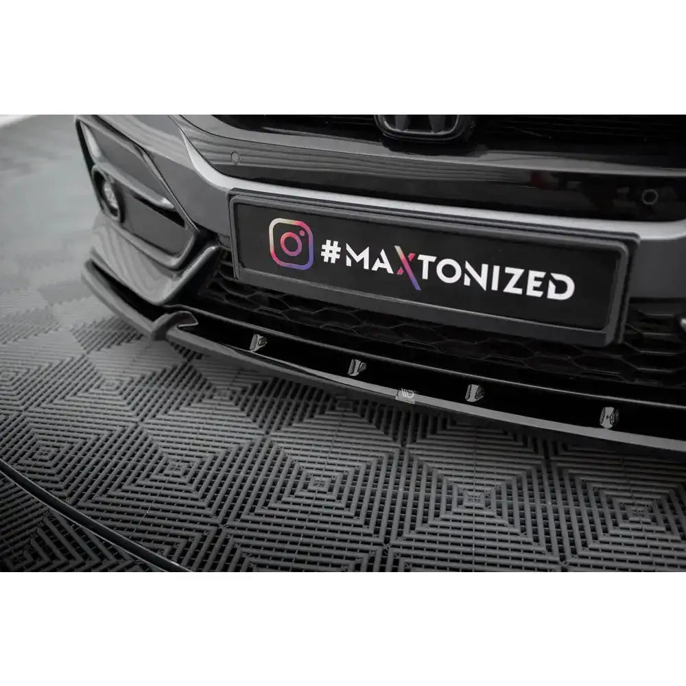 Spoiler Honda Civic Sport Mk 10 i sort blank plast montert på støtfanger, nærbilde med fargerikt skilt.