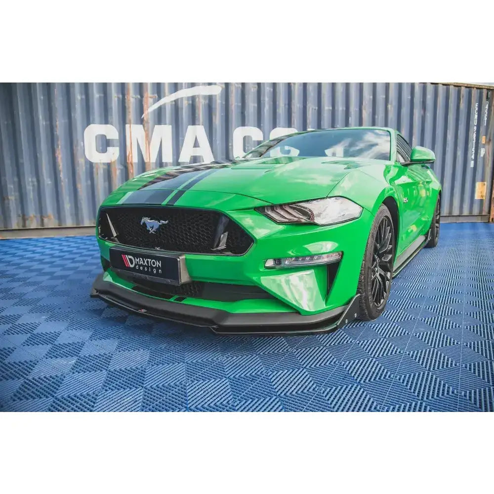 Front splitter på grønn Ford Mustang GT MK6 Facelift med svarte detaljer og blått rutemønstret gulv.