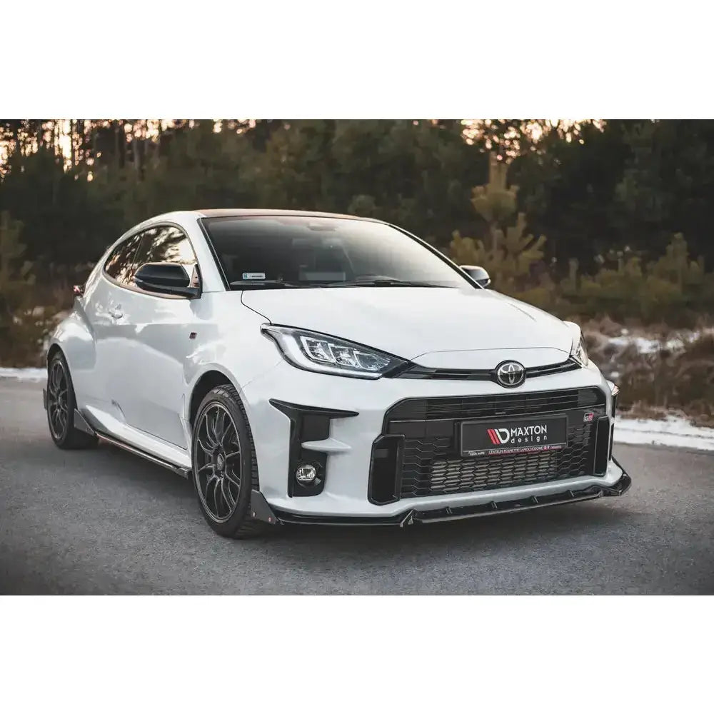 Frontleppe Toyota GR Yaris Mk4 med sorte flaps, vist på hvit sportsbil med mørke felger i naturlig miljø.