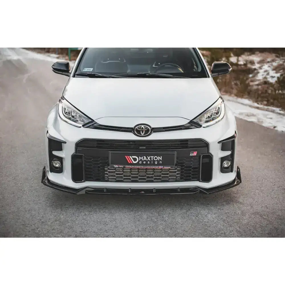 Front splitter på Toyota GR Yaris Mk4 med Maxton Design-logo, hvit lakk og vinterlandskap i bakgrunnen.