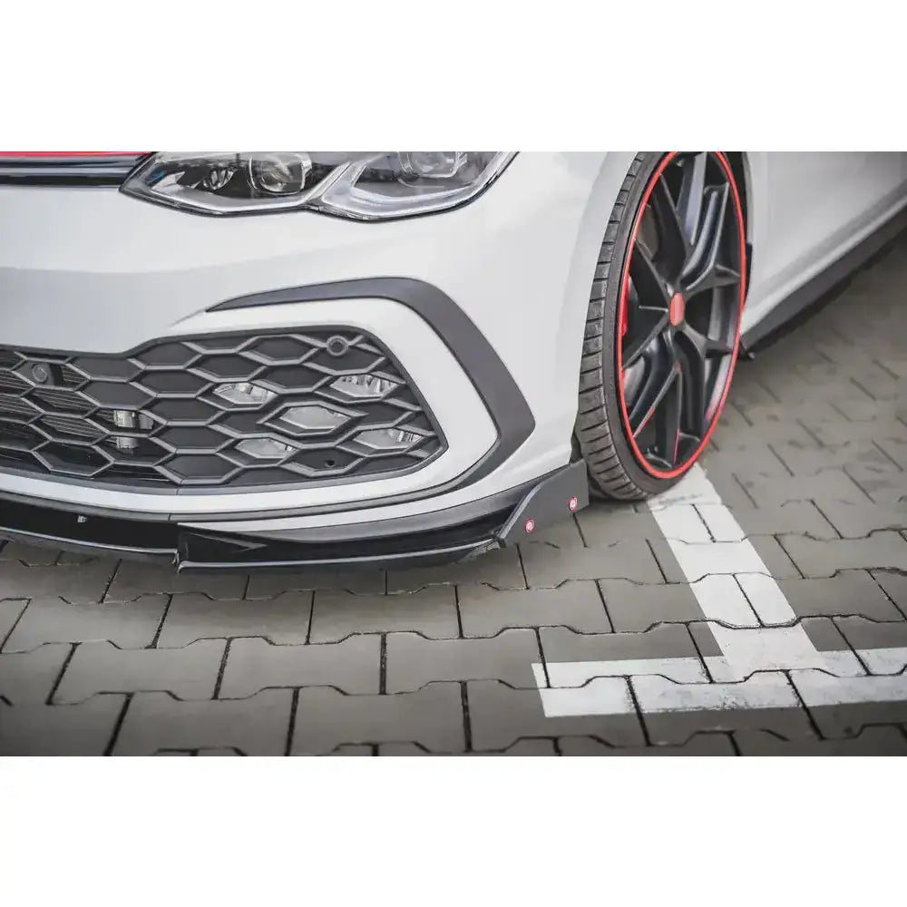 Spoiler Volkswagen Golf 8 GTI 20- nærbilde av sort frontsplitter, grill og svarte felger med rød kant.