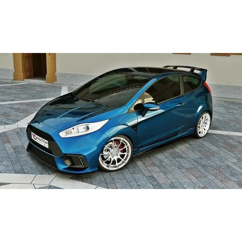 Spoiler på blå Ford Fiesta Mk7 med sorte detaljer og store sølvfelger, sett skrått forfra fra siden.