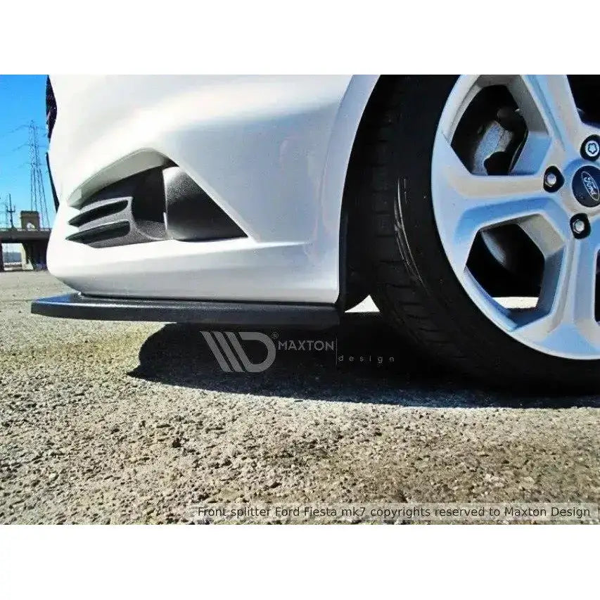 Spoiler til Ford Fiesta Mk7 St Facelift, sort, montert foran høyre forhjul på hvit bil.
