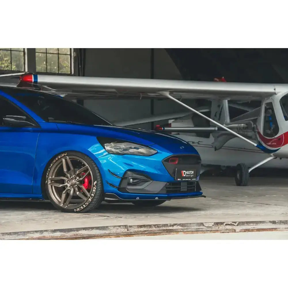 Frontspoiler på blå Ford Focus Mk4 St-Line med svarte detaljer, bronsefargede felger og røde bremsekalipere.