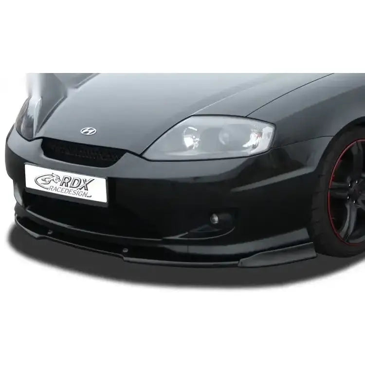 Frontspoiler til Hyundai Coupe GK 05-07 i sort blank plast montert på bil, sett fra skrå frontvinkel.