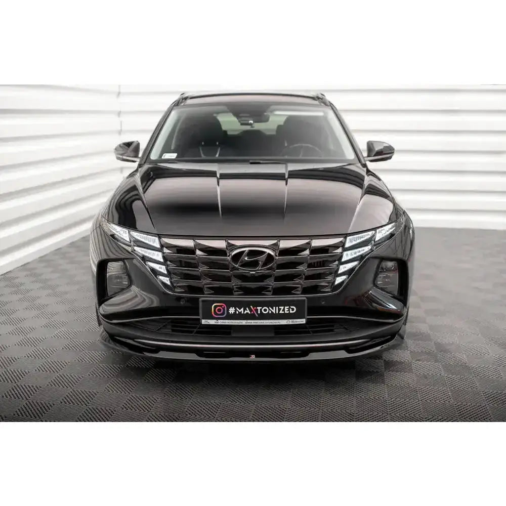 Frontleppe på Hyundai Tucson Mk4 V.1 sett forfra, med sort grill og stilrene frontlykter i lyst rom.