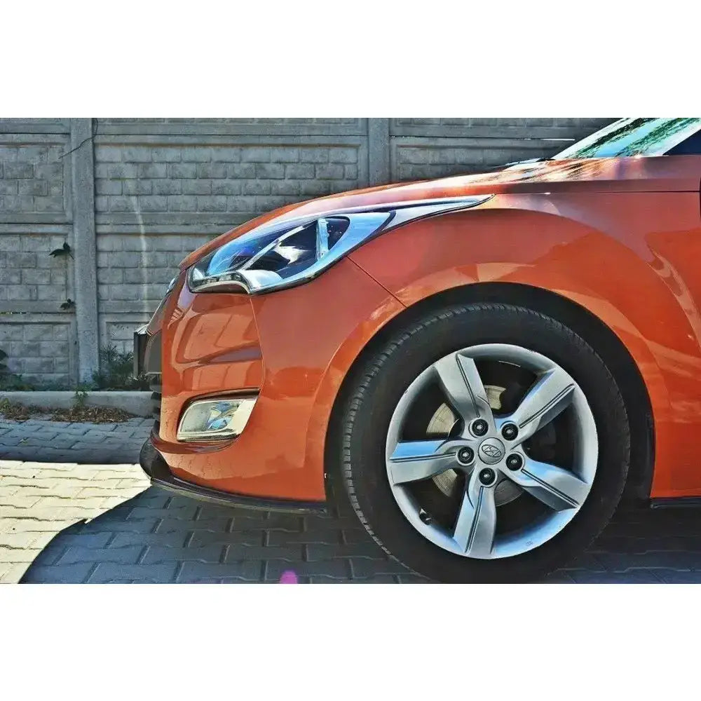 Frontleppe på Hyundai Veloster, oransje bil med kromdetaljer og sølvfarget aluminiumsfelg sett fra siden.