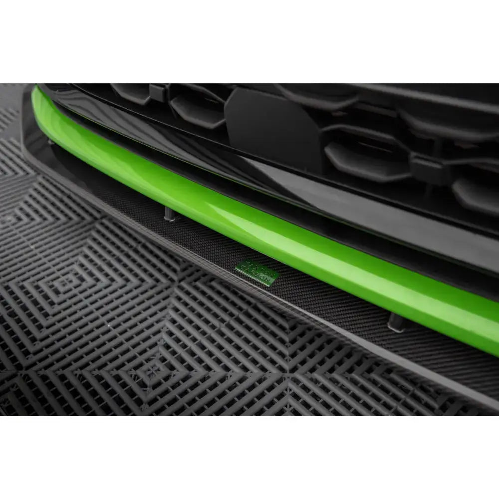 Frontleppe Audi RS3 8Y i grønn karbon, nærbilde fra skrå vinkel med sorte detaljer og plastmønstret gulv.