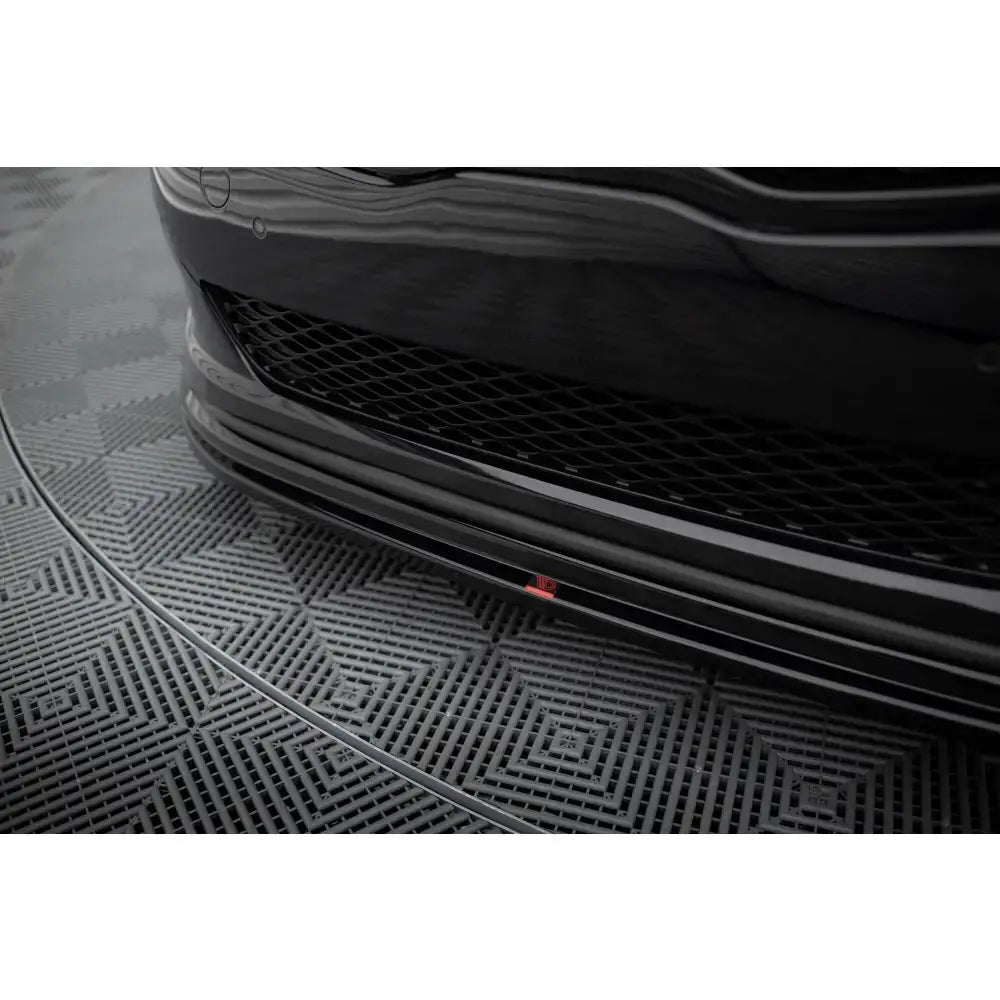 Spoiler til Kia Optima Mk3 i sort blank finish, nærbilde forfra med rød logo og grått gulv.