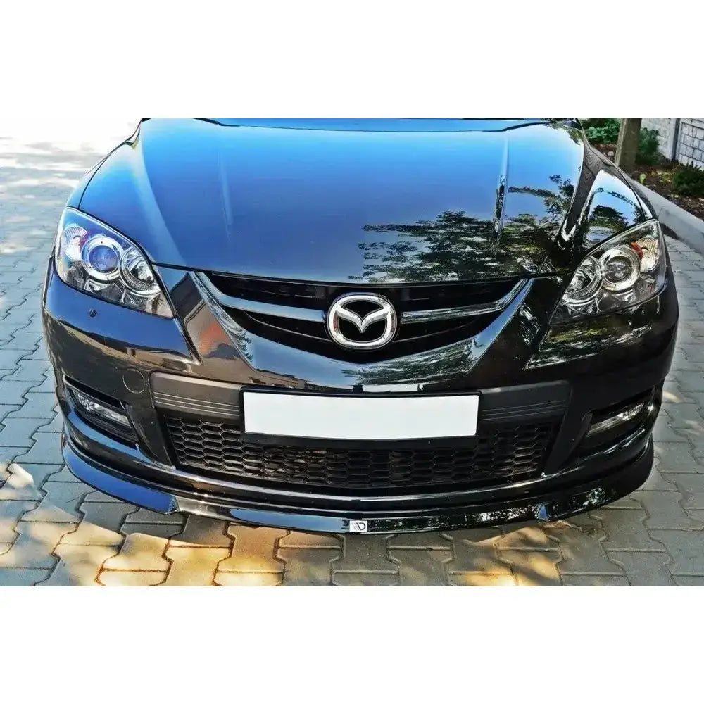 Frontleppe på Mazda 3 MPS Mk1 preface, sort front med grill, emblem og refleksjoner fra dagslys.