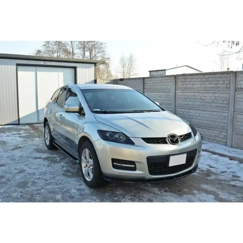 Front splitter på Mazda Cx-7 sølvfarget bil sett skrått forfra med store frontlykter og mørke vinduer.