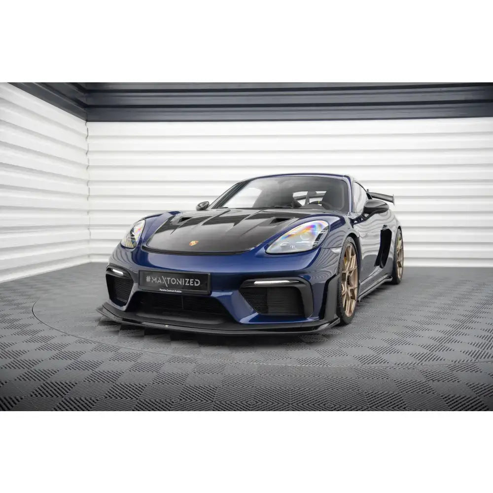 Frontleppe på Porsche 718 Cayman GT4 RS 982c, mørkeblå med sorte og bronsefargede detaljer i garasje.