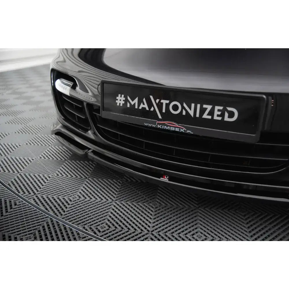 Front splitter på sort Porsche 911 Turbo 997, blank finish, sett fra lav vinkel med skilt "#MAXTONIZED".