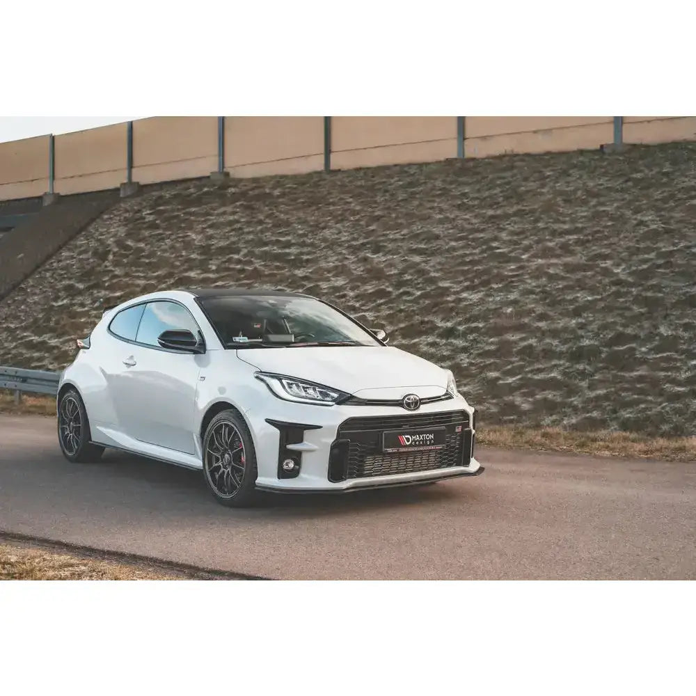 Front lip på Toyota GR Yaris MK4 med markant spoiler, svarte detaljer og aluminiumsfelger på asfaltvei.