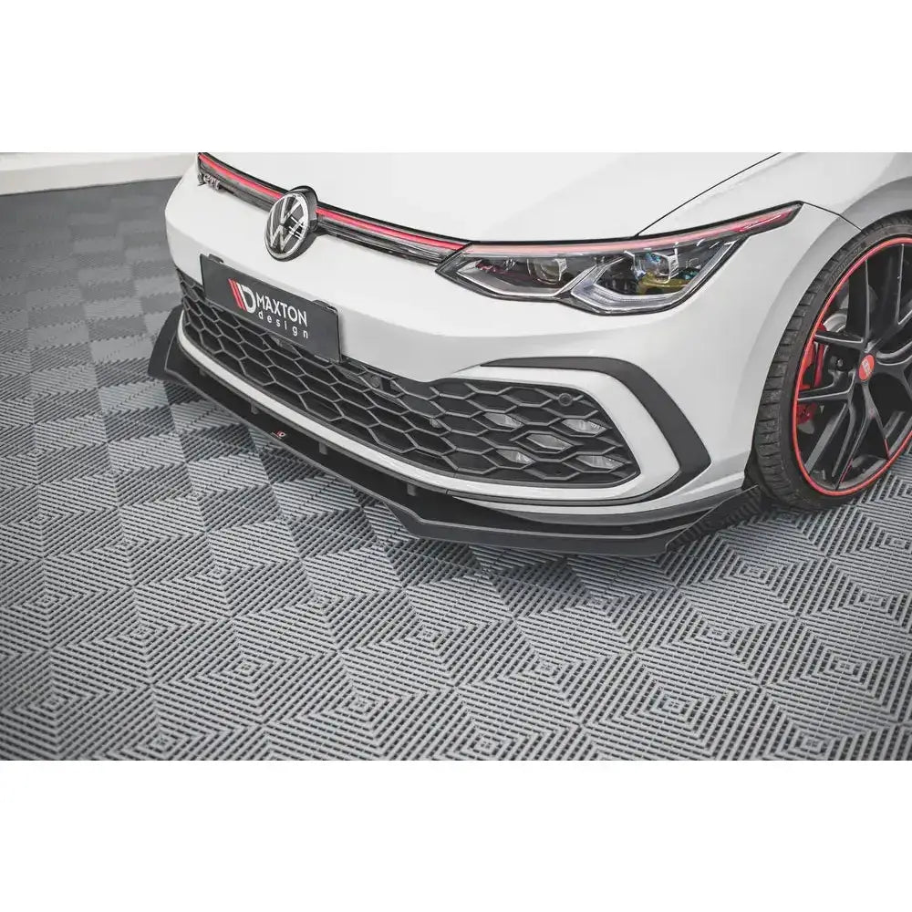 Frontspoiler på Volkswagen Golf 8 GTI med sorte flaps, røde detaljer og mønstret gulv.