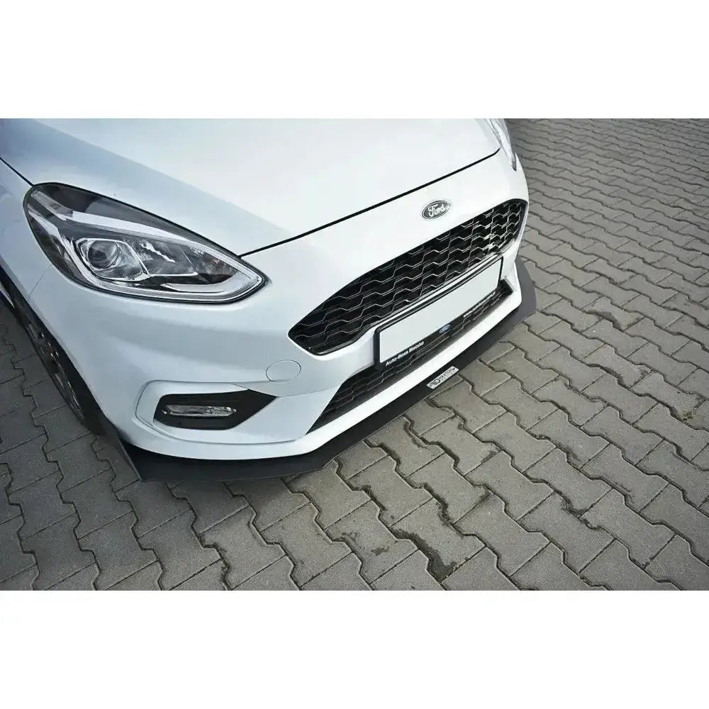 Frontleppe til Ford Fiesta Mk8 med sort racing frontsplitter sett ovenfra på hvit bil på brostein.