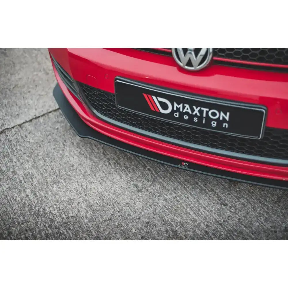 Front lip på Volkswagen Golf GTI MK6 Racing V.3, sort spoiler montert på rød bil med synlig grill og logo.