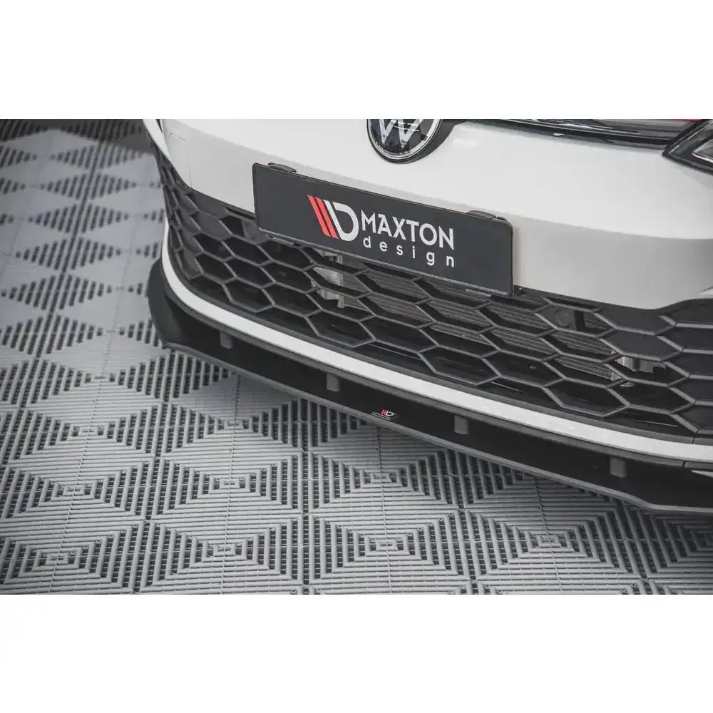 Front splitter for Volkswagen Golf 8 GTI montert under støtfanger, sort plast med Maxton Design-logo.