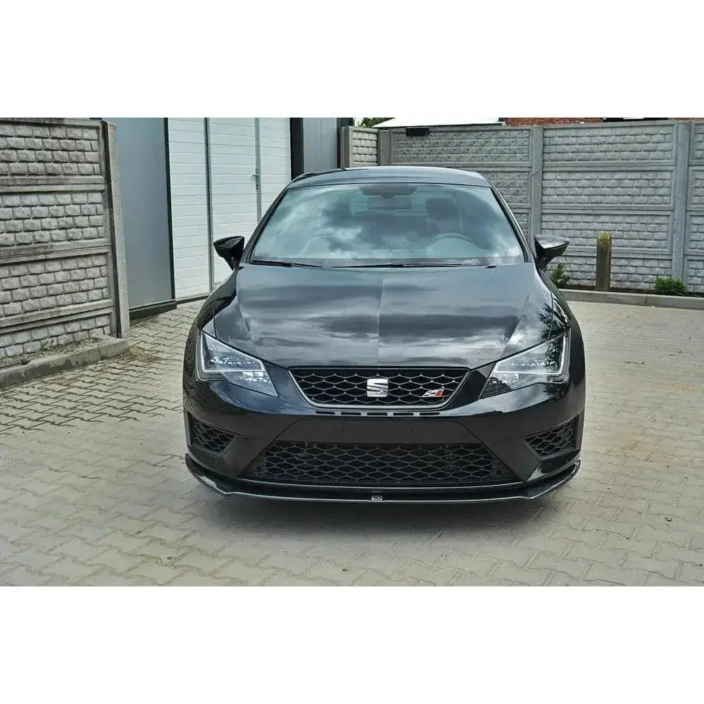 Front lip på Seat Leon III Cupra med sort sporty design, markant grill og parkert foran murvegg.