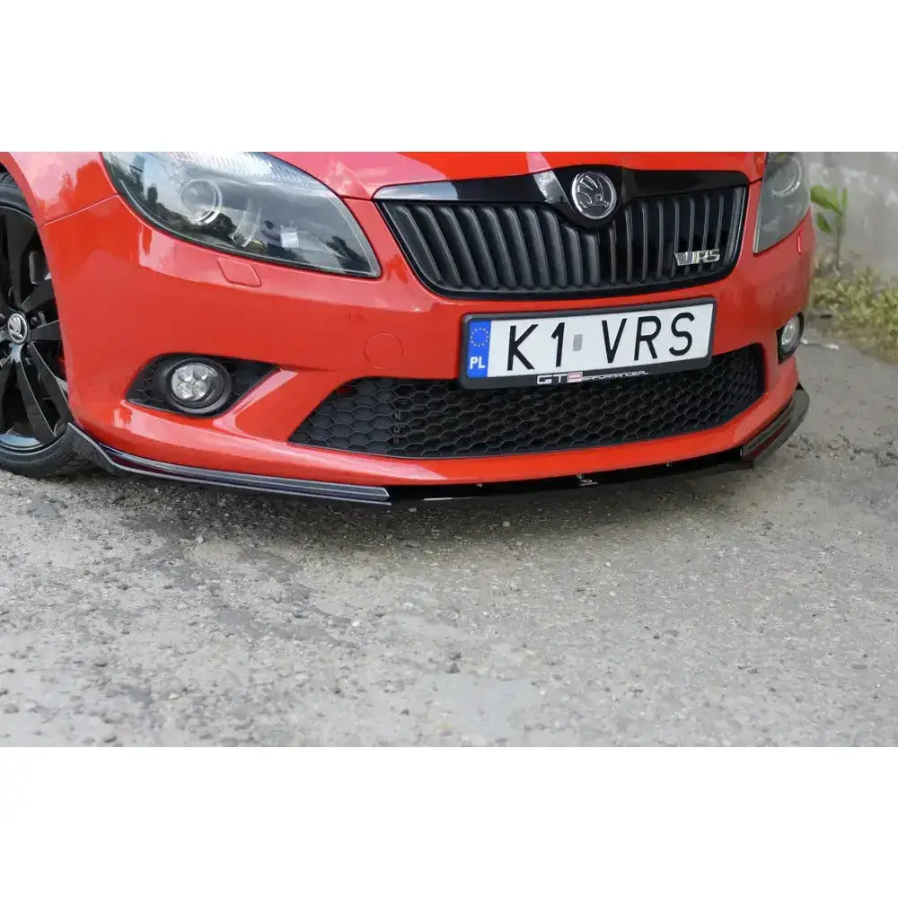 Spoiler til Skoda Fabia Mk2 Rs, sort frontleppe på rød bil med svarte detaljer og synlig bilskilt.