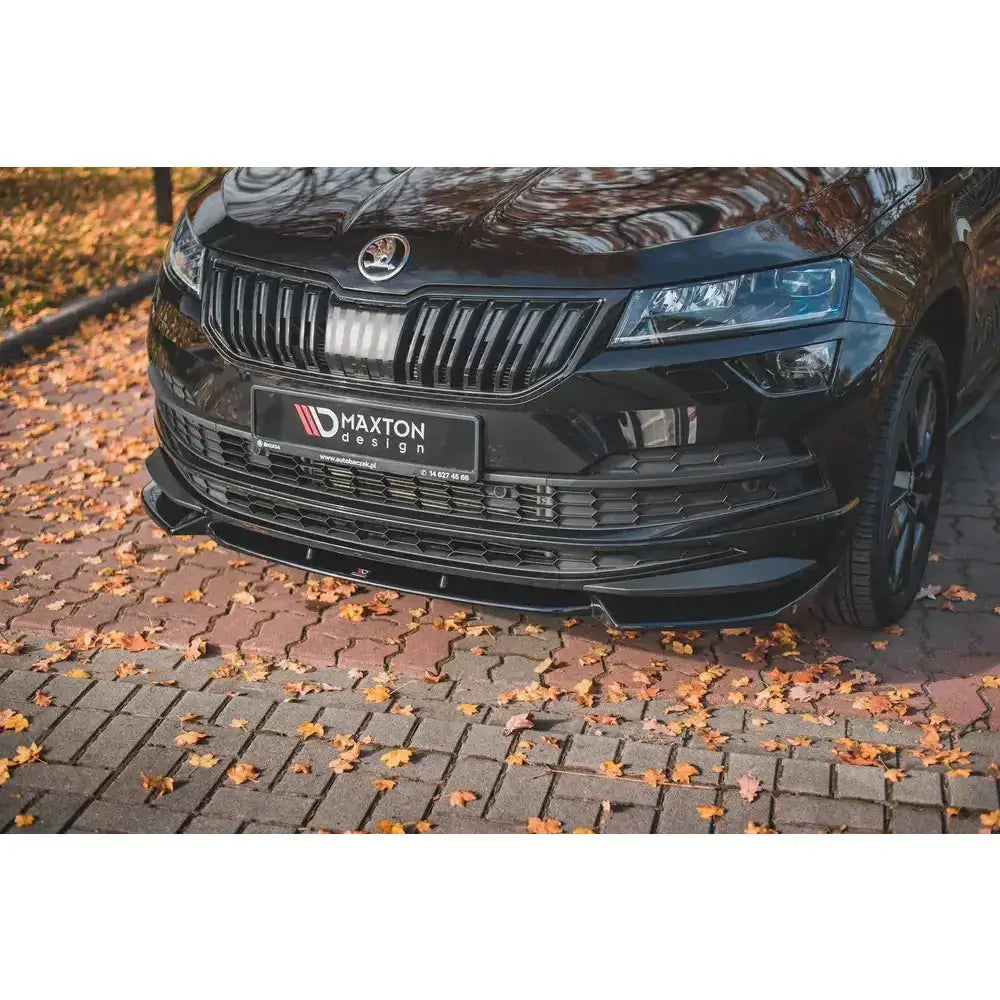 Spoiler til Skoda Karoq Sportline montert foran på bil, sett fra lav vinkel med høstløv på brostein.