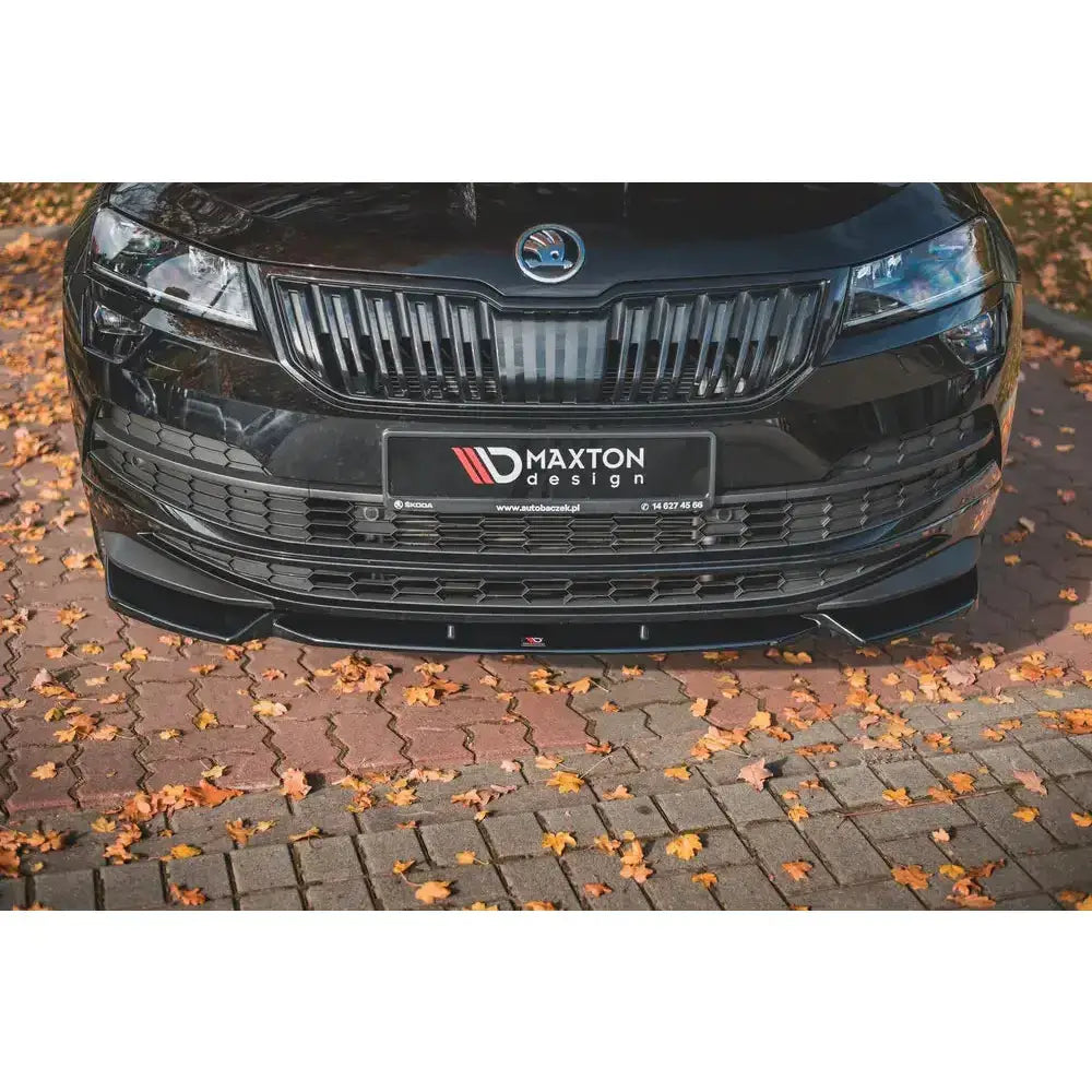 Front splitter på Skoda Karoq Sportline med sort frontspoiler og grill, omgitt av høstløv.