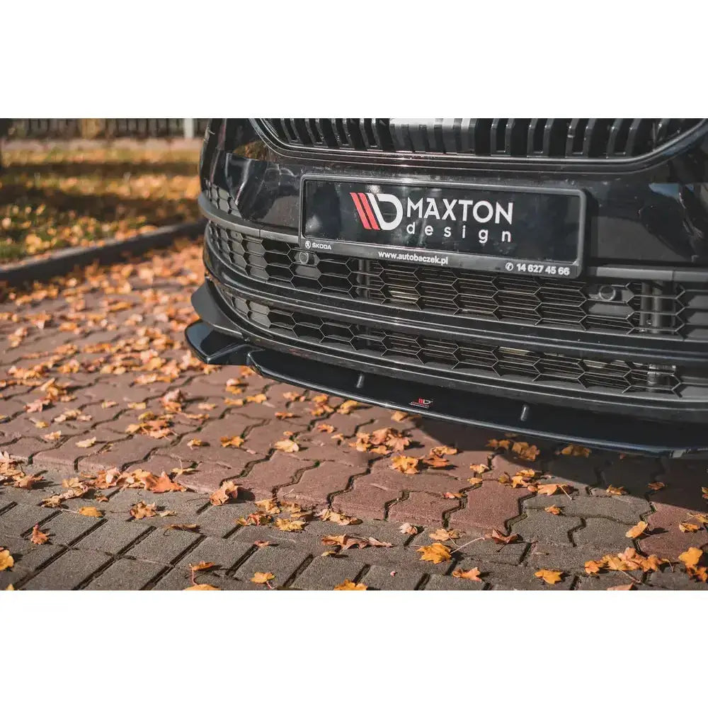 Front lip på Skoda Karoq Sportline, svart frontspoiler montert foran på bilen parkert på brostein.