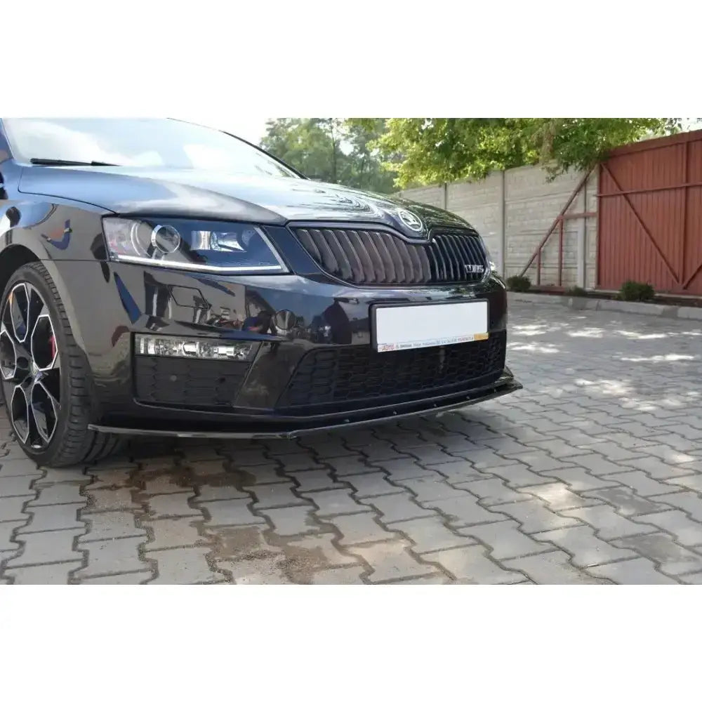 Front splitter på Skoda Octavia III RS, sort bil parkert med spoiler under fronten.